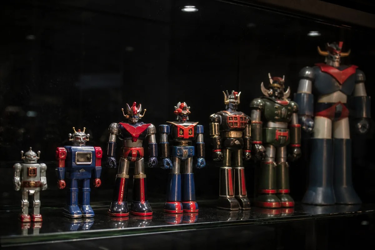 Étagère de collectionneur avec plusieurs robots en métal moulé des années 70 sous lumière rasante