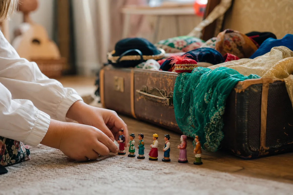 Mains d’enfant disposant des figurines de héros à côté d’une malle de déguisements