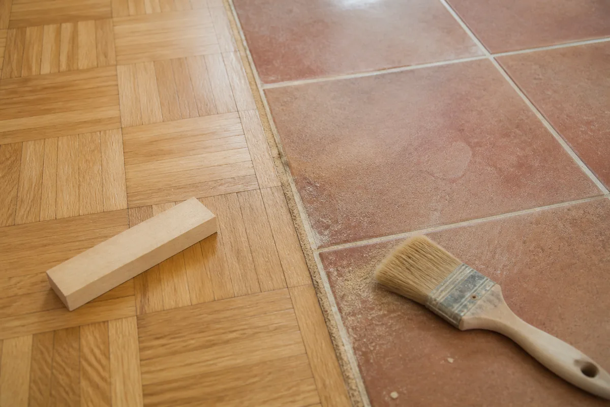 Détail de sol en parquet mosaïque poncé et carrelage grès teinte terre