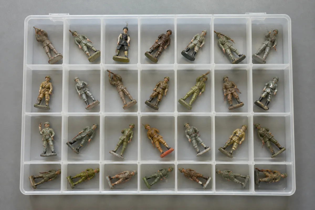 Figurines militaires anciennes rangées dans un bac de conservation en plastique translucide