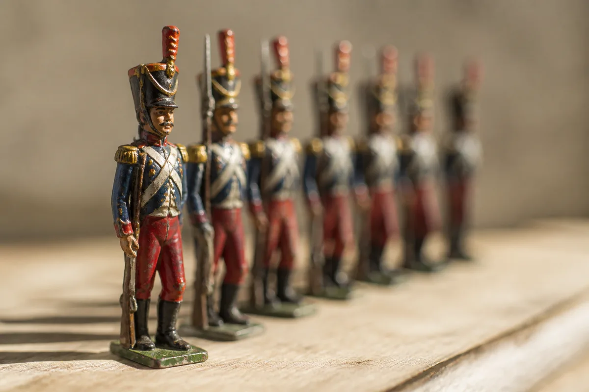 Alignement de petites figurines militaires anciennes peintes à la main sur une table en bois clair