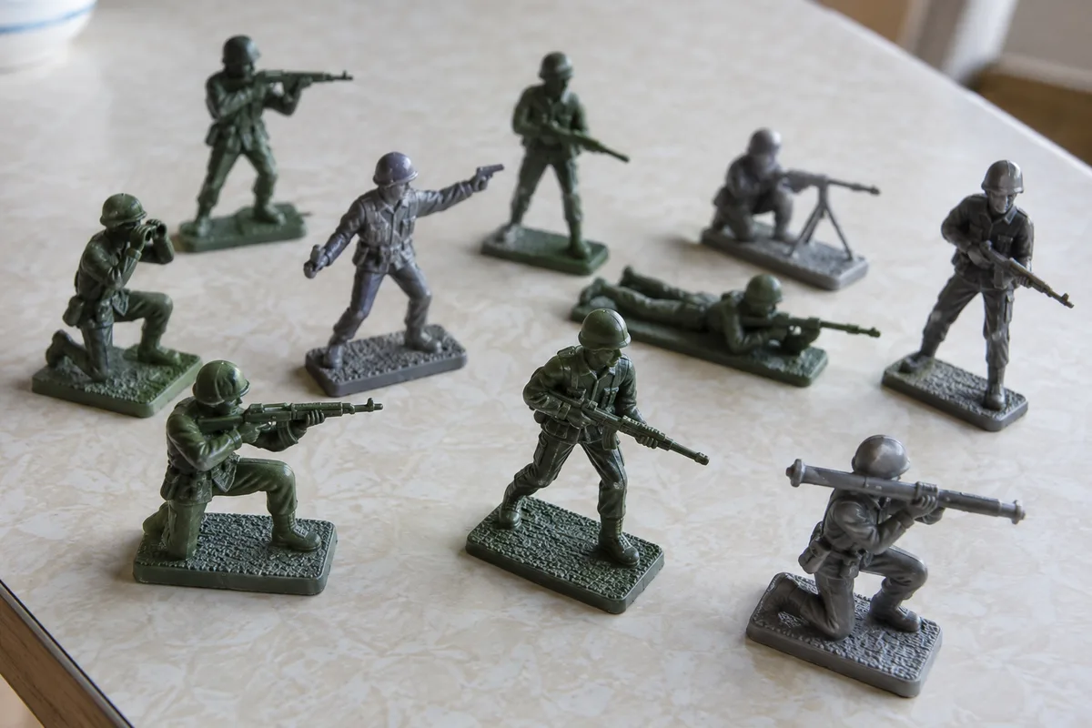 Petites figurines militaires en plastique posées sur une table claire, socles rectangulaires visibles